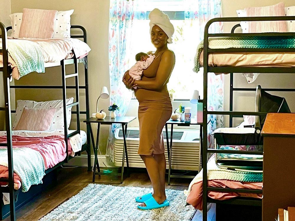 Woman smiling with baby standing in the middle of 2 bunkbeds