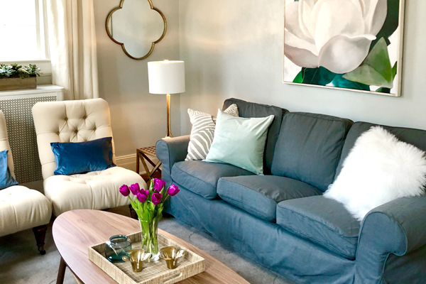 A nicely renovated room with a blue couch and two lighter colored sitting chairs
