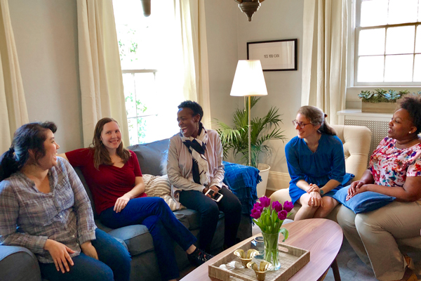 A group of women sitting around a table on couches smiling