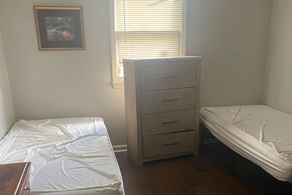 Room makeover before of 2 beds with a dresser in the middle