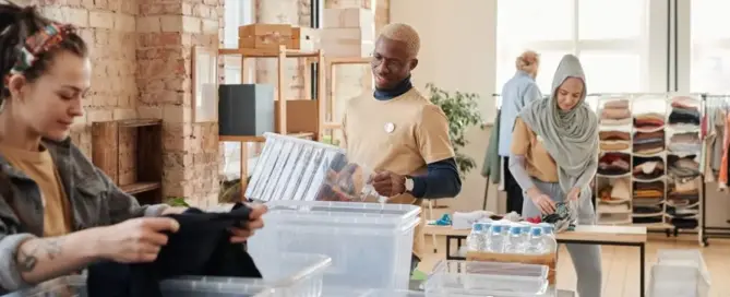 Volunteers organizing clothing and product donations for nonprofits in a bright warehouse